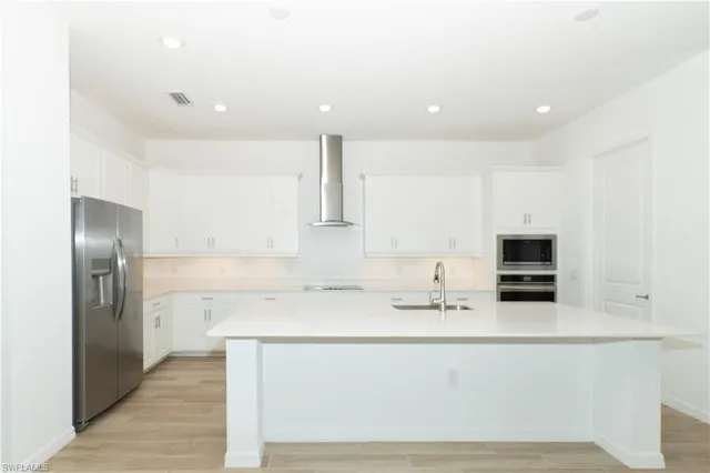 a kitchen with stainless steel appliances kitchen island granite countertop a refrigerator and a sink