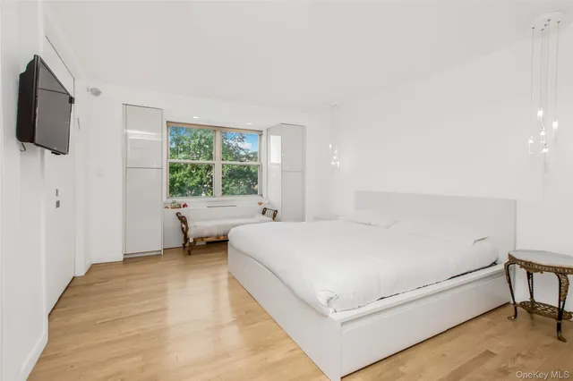 a bedroom with a bed a flat screen tv and window