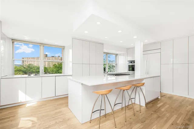 a kitchen with stainless steel appliances kitchen island granite countertop a refrigerator a stove a sink and white cabinets with wooden floor