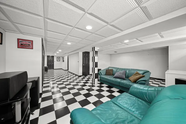 a living room with a black white checkered floor with couches chair and a coffee table