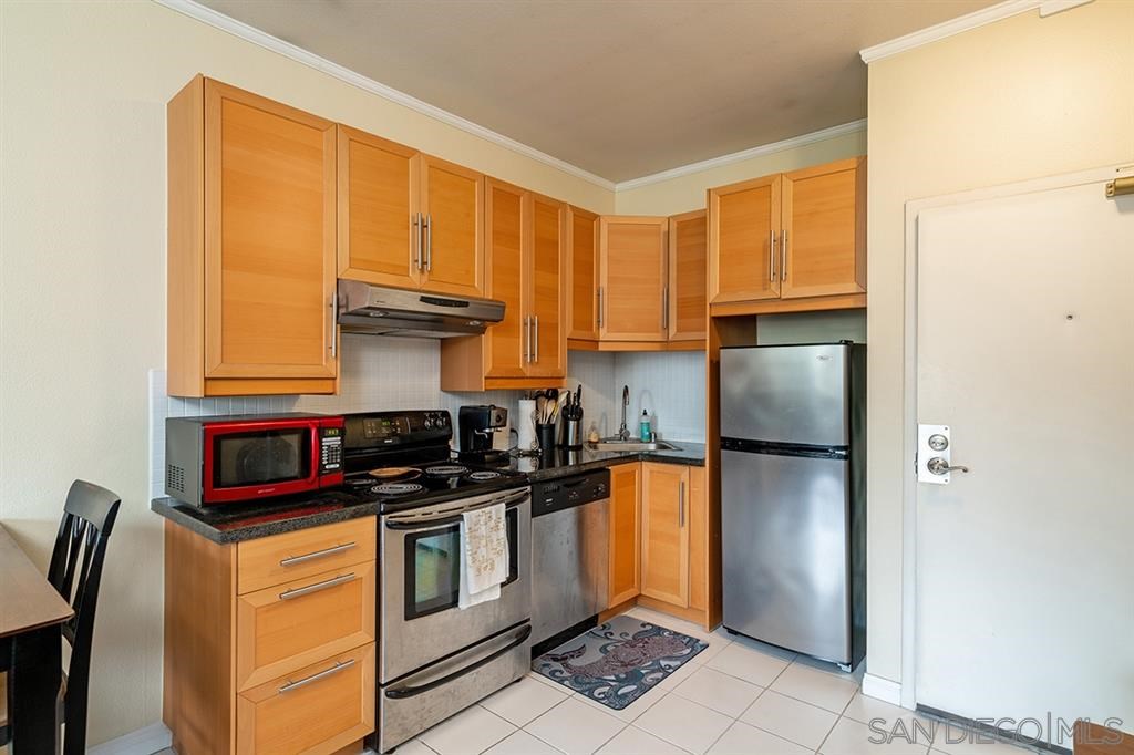 2650 Broadway, Unit 314 San Diego, CA 92102 - Photo 6 of 16 a kitchen with stainless steel appliances granite countertop a refrigerator a stove and a sink with wooden floor