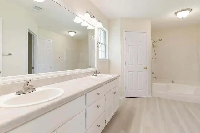 a bathroom with a sink double vanity granite tub and a mirror