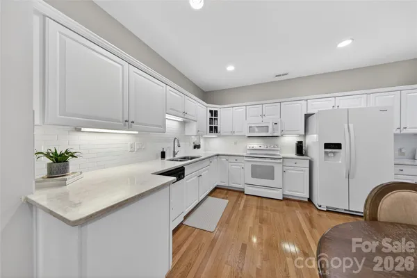 a kitchen with granite countertop a sink stainless steel appliances and white cabinets