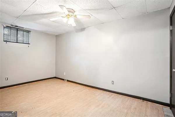 an empty room with a chandelier fan and windows