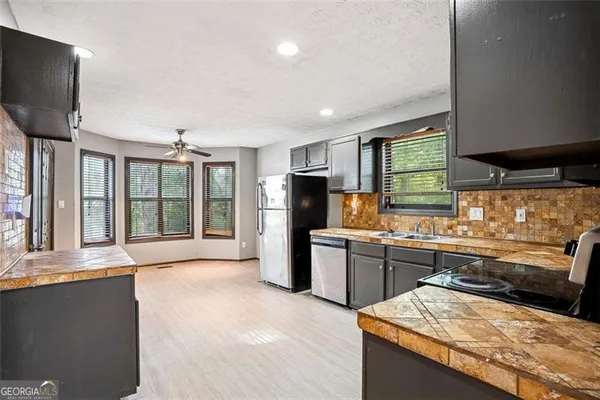 a large kitchen with kitchen island granite countertop a large counter top stainless steel appliances a sink and a large window