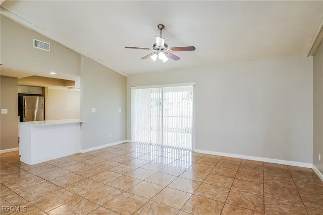 a view of an empty room with window and chandelier fan