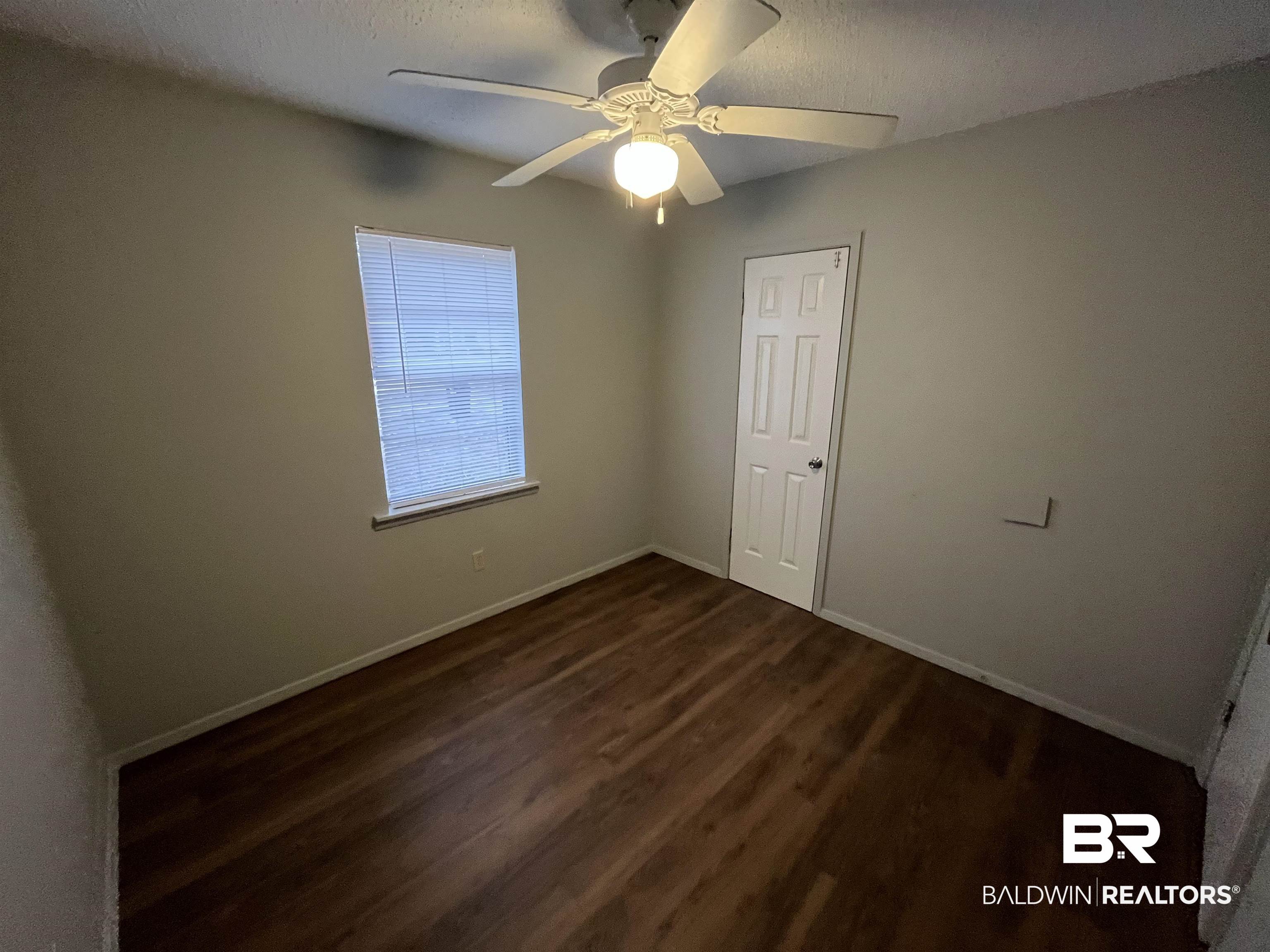 103 Roadway Street Brewton, AL 36426 - Photo 11 of 13 Spare room featuring a textured ceiling, ceiling fan, and dark hardwood / wood-style floors
