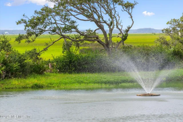 a view of a brick building next to a big yard and large trees