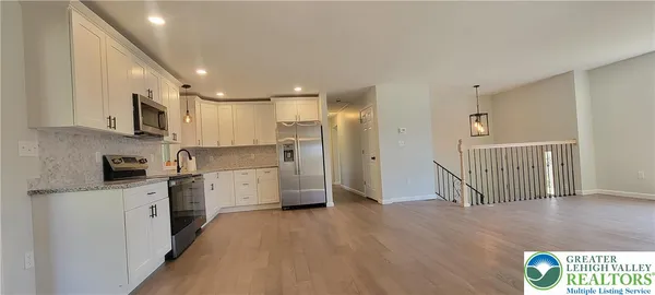 a view of a kitchen with stainless steel appliances wooden floor and a window