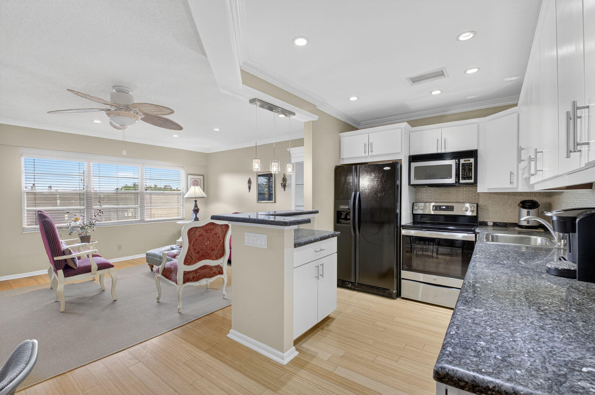 a kitchen with stainless steel appliances kitchen island granite countertop a refrigerator a stove a sink a dining table and chairs with wooden floor