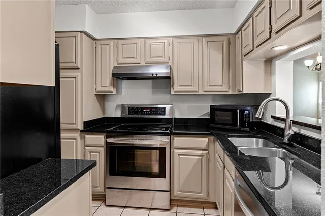 a kitchen with granite countertop a stove sink and cabinets