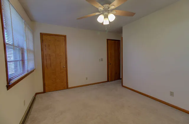 an empty room with a chandelier fan and windows