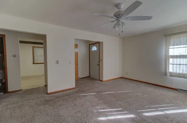 an empty room with windows and fan