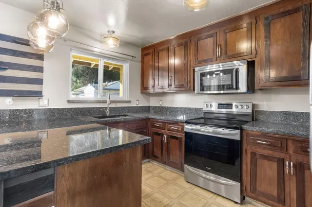 a kitchen with stainless steel appliances granite countertop a stove microwave and sink