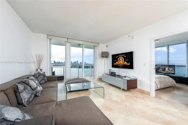 a living room with furniture flat screen tv and a large window