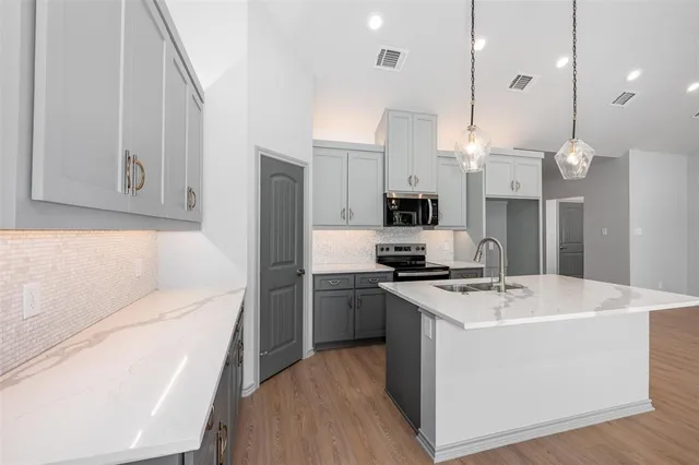 a kitchen that has a sink a stove and wooden floor