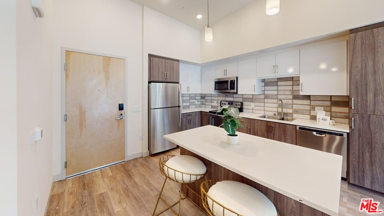 950 East 3rd Street, Unit 2228 Los Angeles, CA 90013 - Photo 5 of 7 a kitchen with stainless steel appliances a refrigerator a sink a stove a microwave a dining table and chairs