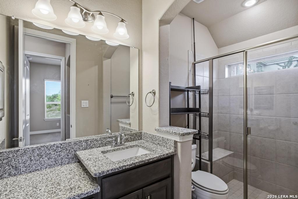 287 Cascade Trail Castroville, TX 78009 - Photo 26 of 46 a bathroom with a granite countertop sink toilet a mirror and shower