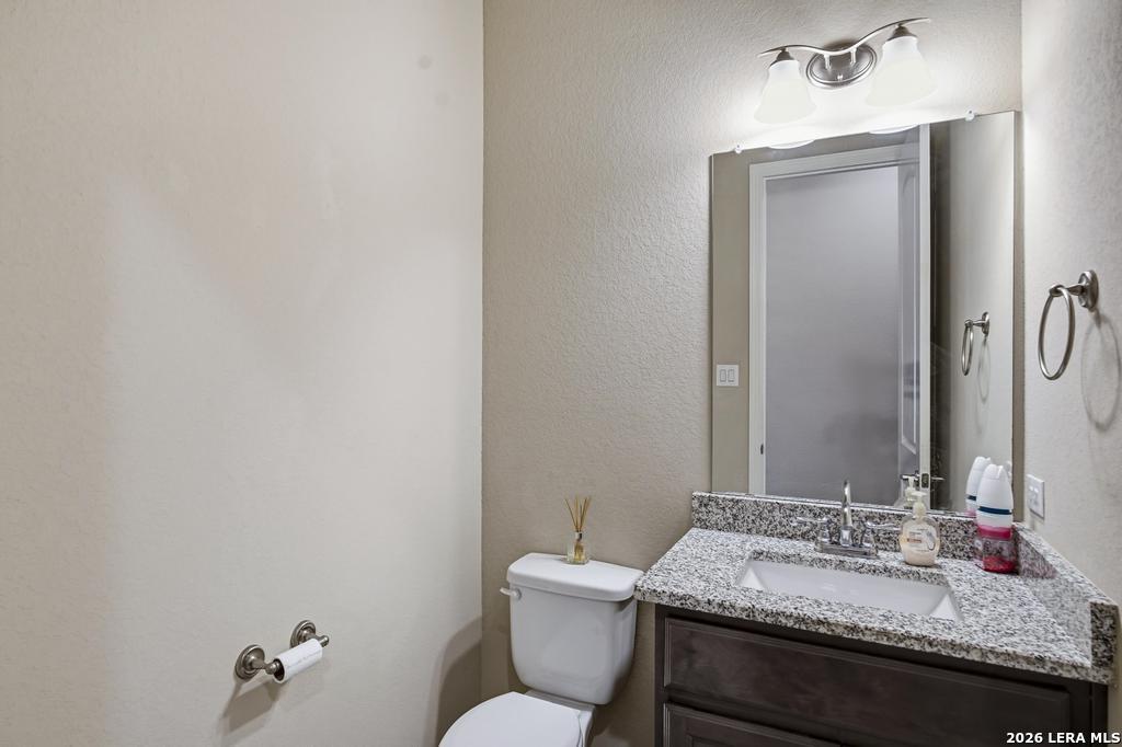 287 Cascade Trail Castroville, TX 78009 - Photo 32 of 46 a bathroom with a granite countertop sink and a mirror with toilet