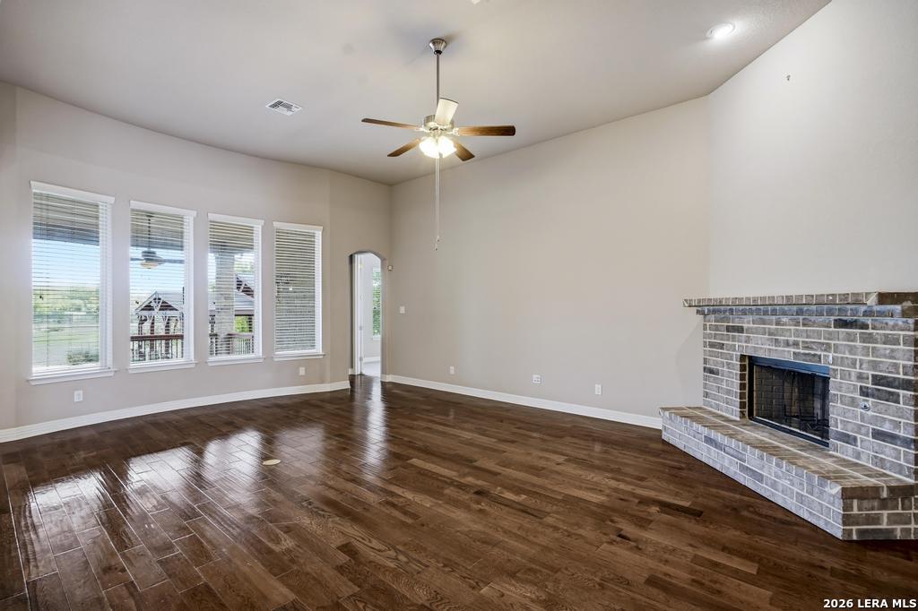 287 Cascade Trail Castroville, TX 78009 - Photo 8 of 46 an empty room with windows fireplace and wooden floor