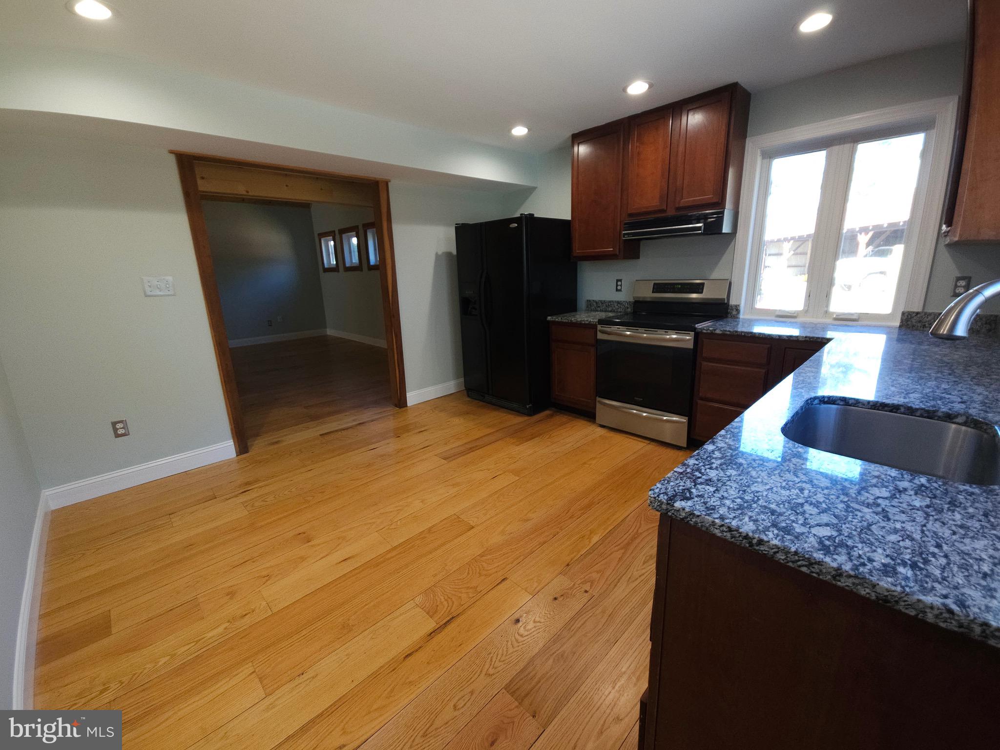 13256 Golden Drive Sumerduck, VA 22742 - Photo 8 of 27 a kitchen with stainless steel appliances kitchen island granite countertop a refrigerator oven a sink with wooden cabinets and wooden floor