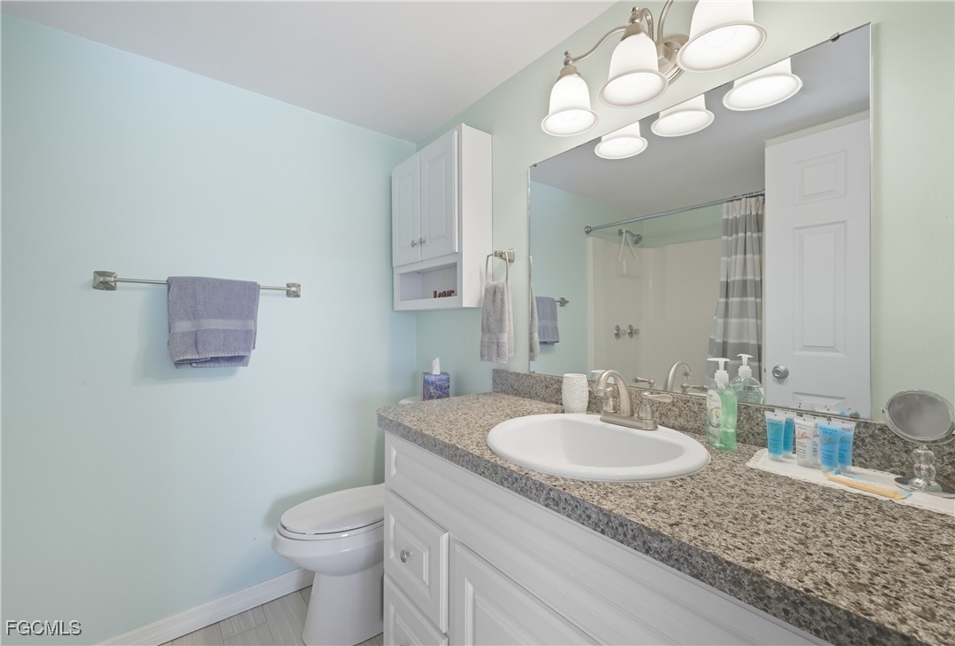 16881 Davis Road, Unit 126 Fort Myers, FL 33908 - Photo 19 of 27 a bathroom with a granite countertop sink a toilet and mirror