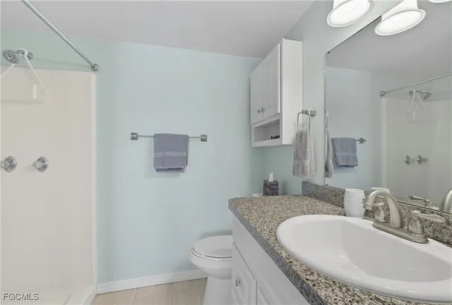 a bathroom with a granite countertop sink a toilet and a mirror