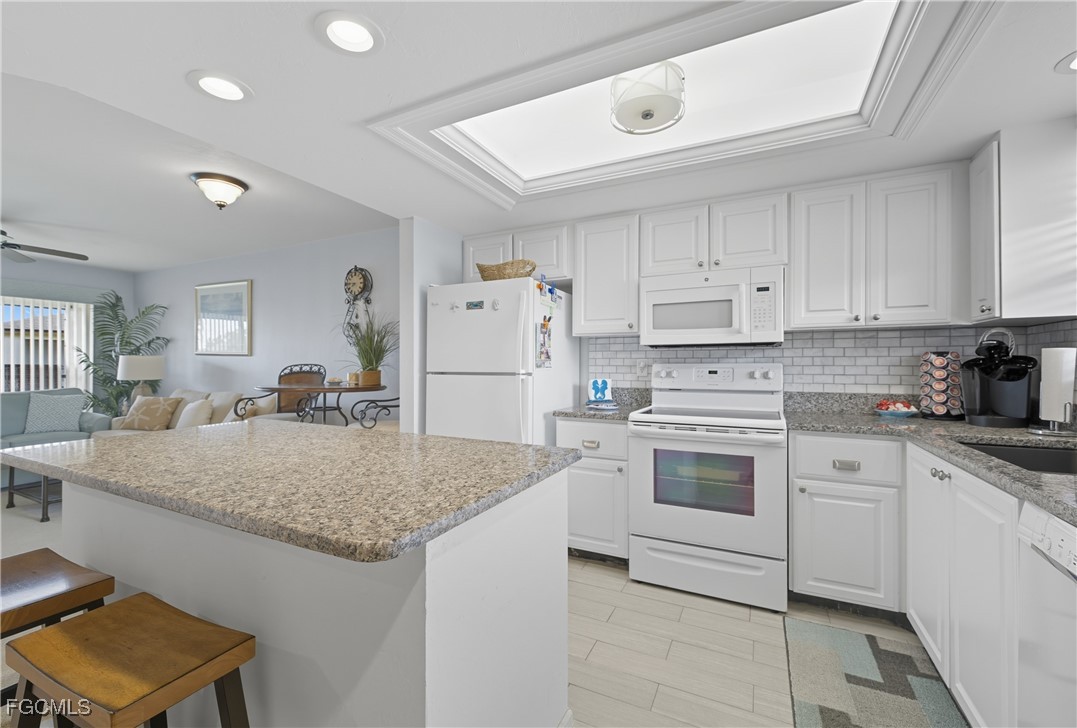 16881 Davis Road, Unit 126 Fort Myers, FL 33908 - Photo 4 of 27 a kitchen with granite countertop a sink stove and white cabinets