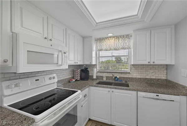 a kitchen with white cabinets and appliances
