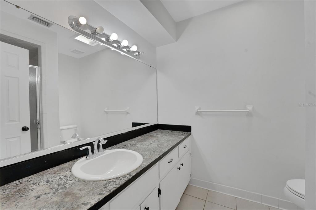 404 Lake Ned Road Winter Haven, FL 33884 - Photo 15 of 18 a bathroom with a granite countertop sink a toilet and mirror