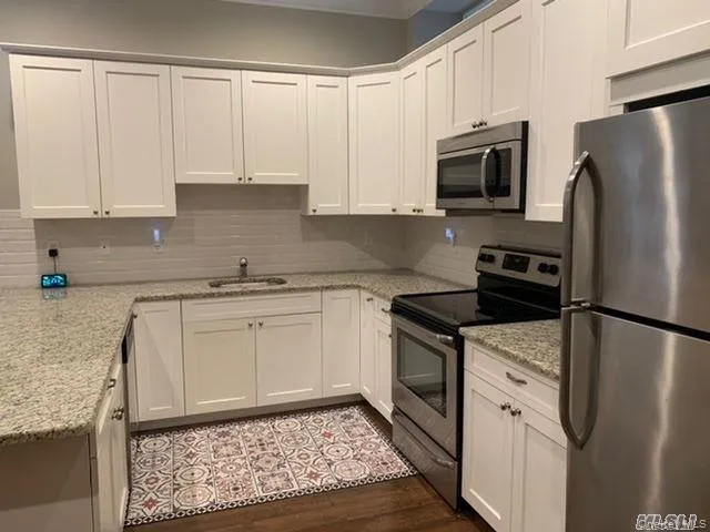 a kitchen with stainless steel appliances granite countertop a refrigerator stove top oven and sink