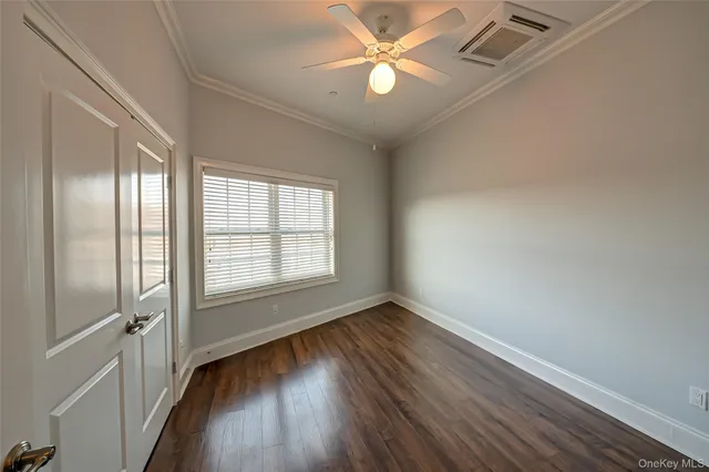 an empty room with wooden floor fan and windows