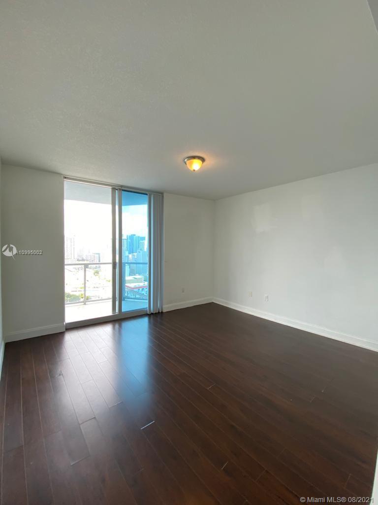 185 Southwest 7th Street, Unit 3403 Miami, FL 33130 - Photo 12 of 34 a view of an empty room with wooden floor and a window