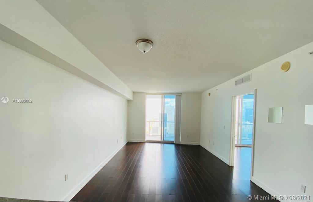 185 Southwest 7th Street, Unit 3403 Miami, FL 33130 - Photo 6 of 34 a view of an empty room with wooden floor and a window