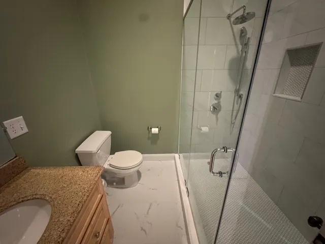 a bathroom with a granite countertop sink a toilet and shower
