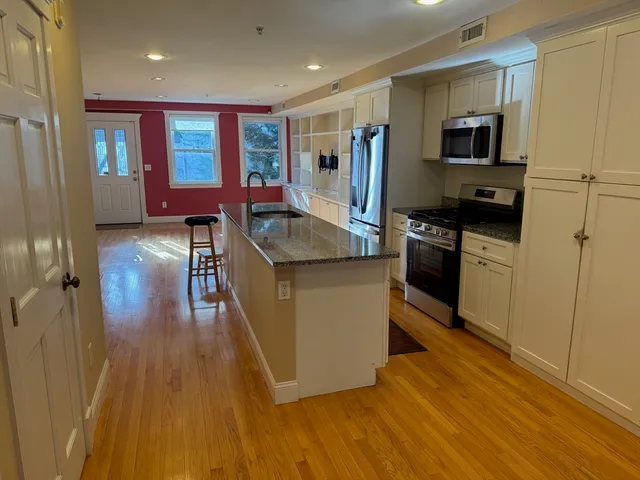a kitchen with sink a refrigerator and wooden floor