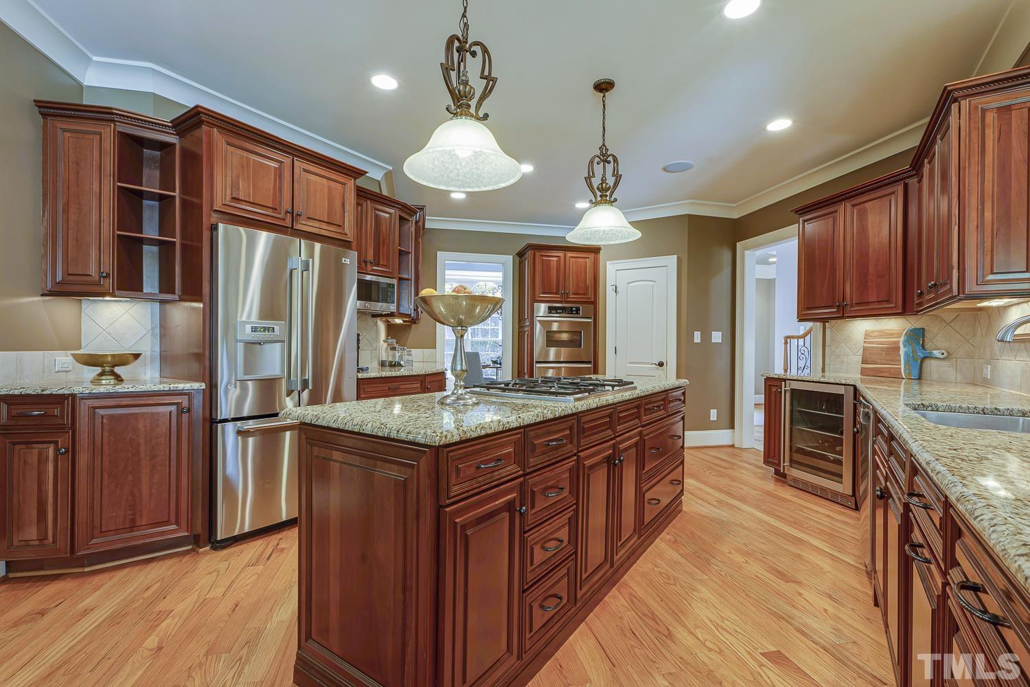 5201 Rathkeale Court Holly Springs, NC 27540 - Photo 17 of 46 a kitchen with stainless steel appliances wooden cabinets a stove and a refrigerator