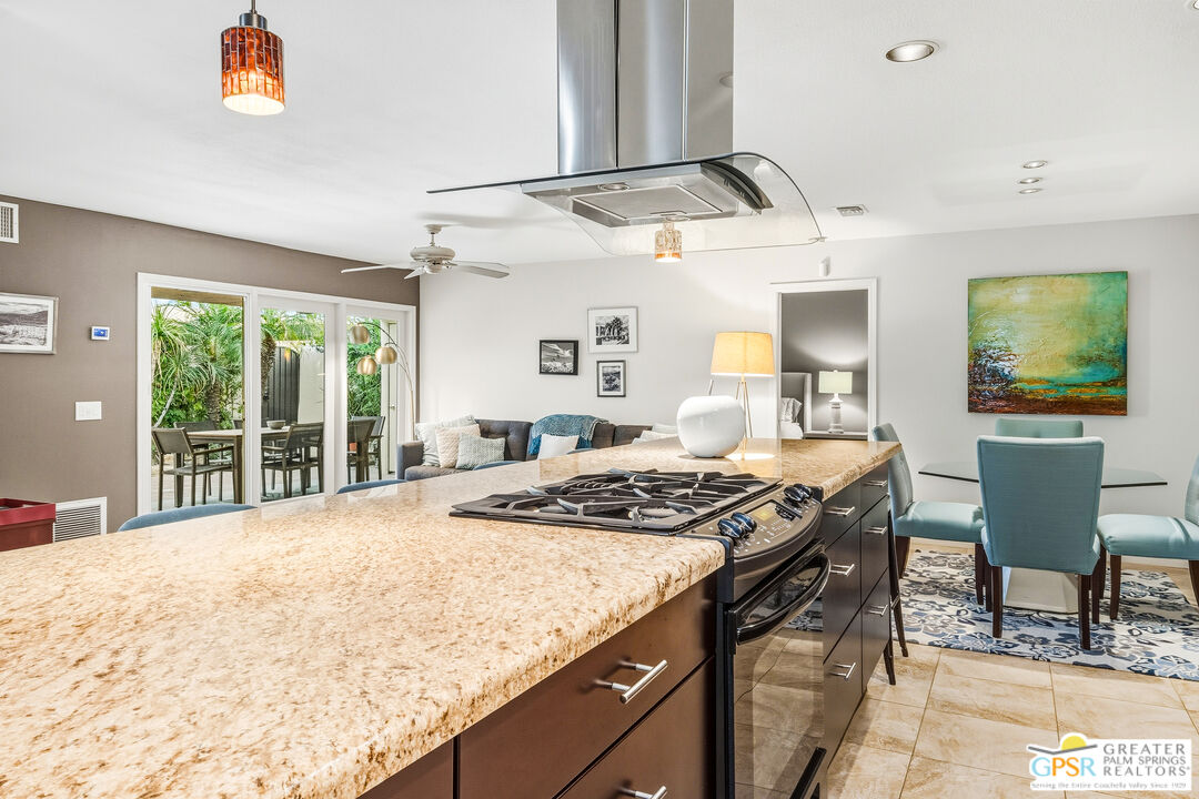 1103 East Alejo Road Palm Springs, CA 92262 - Photo 11 of 39 a kitchen with a stove a sink a dining table and chairs with wooden floor