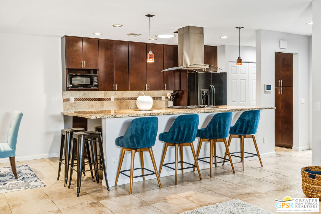 1103 East Alejo Road Palm Springs, CA 92262 - Photo 12 of 39 a kitchen with stainless steel appliances kitchen island granite countertop a table chairs and a refrigerator