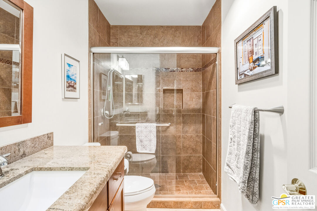 1103 East Alejo Road Palm Springs, CA 92262 - Photo 25 of 39 a bathroom with a granite countertop sink a toilet a mirror and shower
