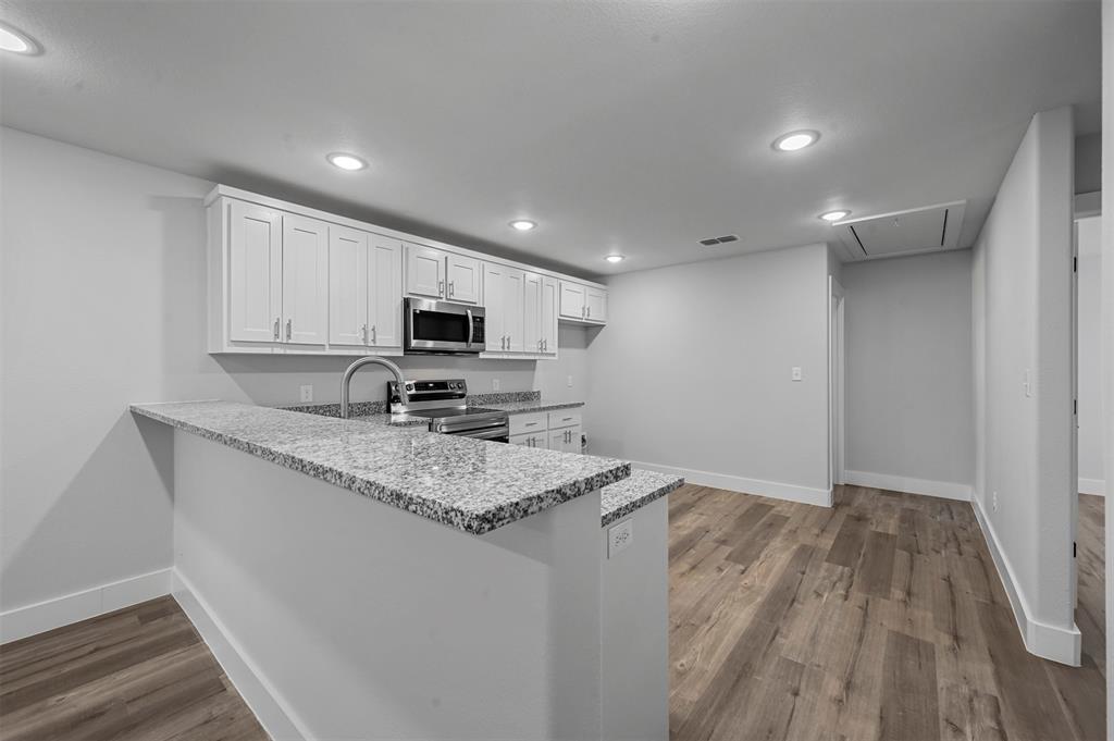 522 East 5th Street, Unit 1 Bonham, TX 75418 - Photo 3 of 19 a kitchen with granite countertop a sink stainless steel appliances and white cabinets