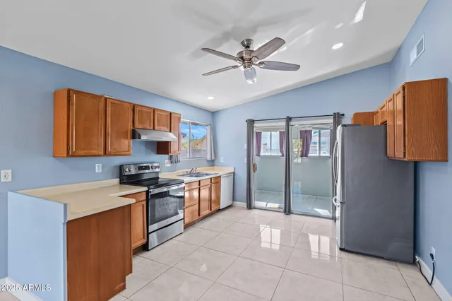 a kitchen with stainless steel appliances granite countertop a stove top oven a sink a refrigerator and island