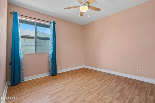 an empty room with wooden floor fan and windows