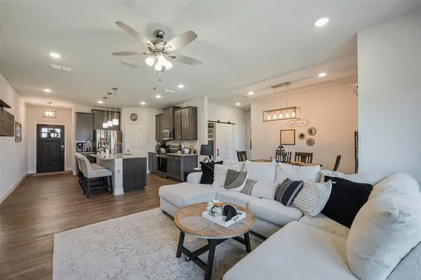 a living room with furniture kitchen view and a chandelier