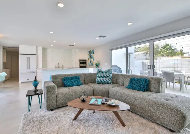 a large white kitchen with lots of white cabinets a sink a dining table and chairs