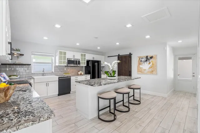 a kitchen with stainless steel appliances granite countertop a stove top oven a sink dishwasher a refrigerator and cabinets with wooden floor