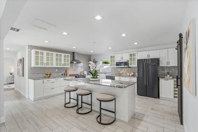 a kitchen with stainless steel appliances kitchen island granite countertop a refrigerator and a stove top oven
