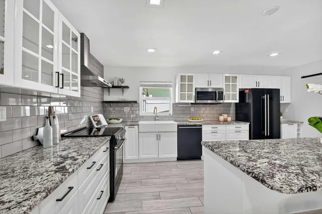a large kitchen with stainless steel appliances granite countertop a stove refrigerator and a sink