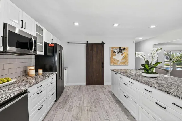 a kitchen with granite countertop white cabinets and white appliances