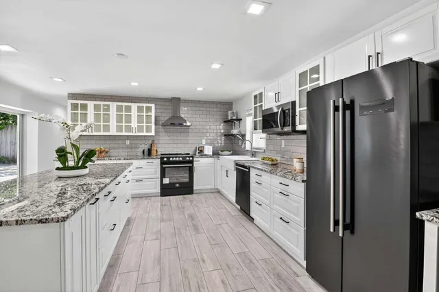a kitchen with stainless steel appliances kitchen island granite countertop a refrigerator and a stove top oven